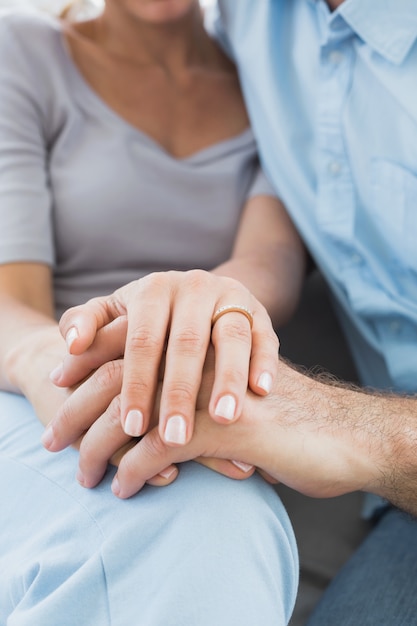 Coppie che mostrano fede nuziale sul dito della donna sul divano