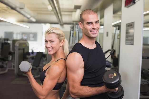 Coppie che si esercitano con i dumbbells in ginnastica