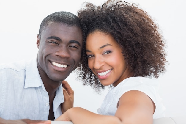 Coppie che si siedono insieme sullo strato che sorride alla macchina fotografica