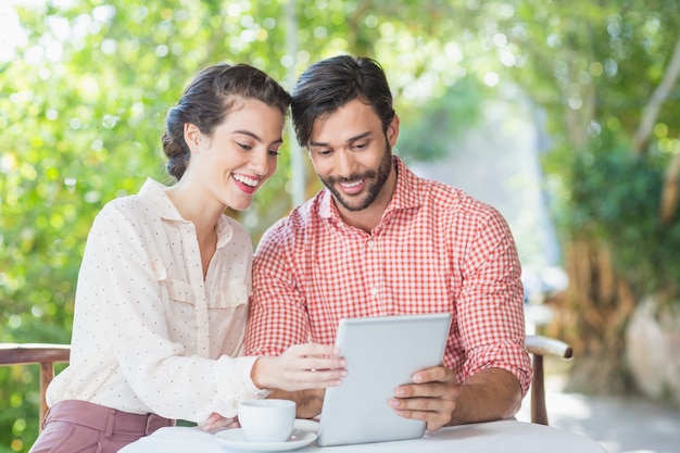 Coppie che sorridono mentre per mezzo della compressa digitale