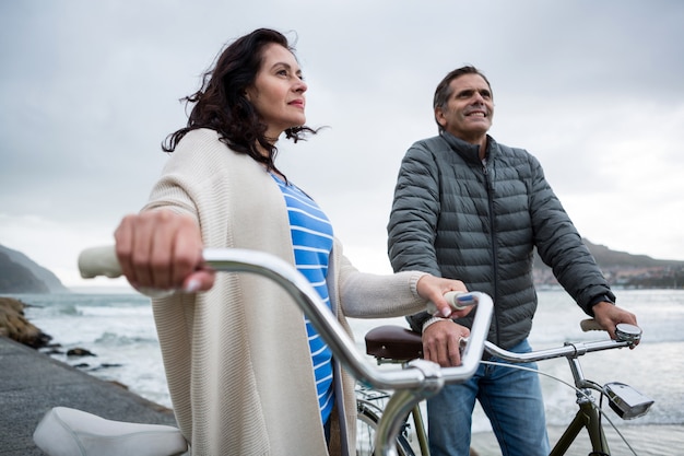 Coppie che stanno con la bicicletta sulla spiaggia