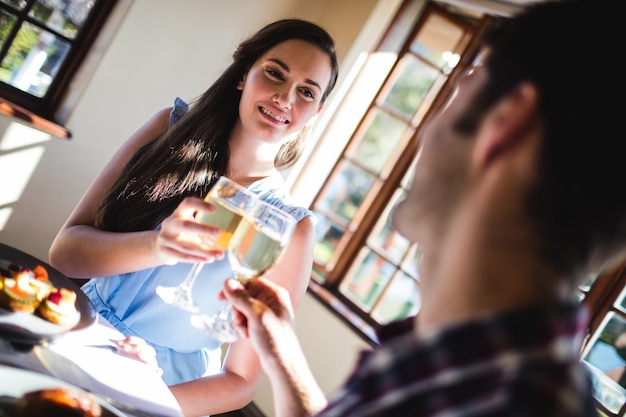 Coppie che tostano il bicchiere di vino bianco in ristorante