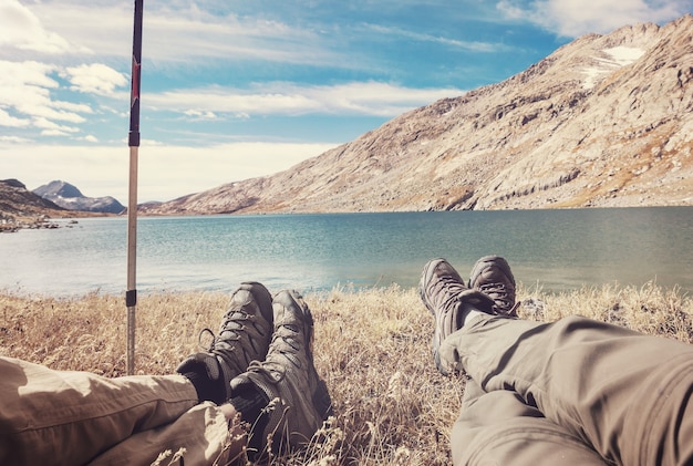 Coppie del viaggiatore che si rilassano dopo l'escursione vicino al lago delle montagne.