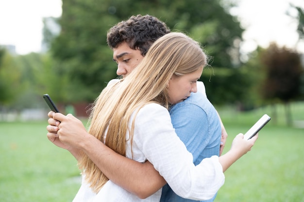 Coppie dell'adolescente che abbracciano e usano i telefoni