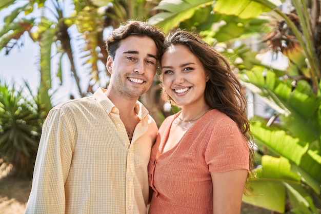 Coppie della donna e dell'uomo che sorridono fiduciose e che si abbracciano al parco