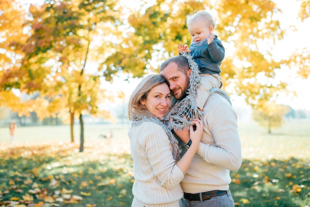 Coppie della famiglia che abbracciano nel parco all'aperto con il loro fare da baby-sitter sulle spalle dei padri