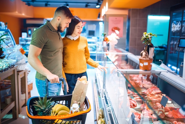 Coppie della famiglia che scelgono carne fresca refrigerata in drogheria