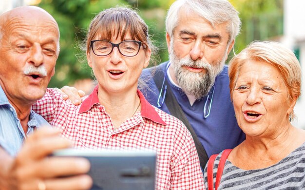 Coppie di anziani che si fanno selfie con lo smartphone Riunione di vecchi amici che si divertono all'aperto insieme