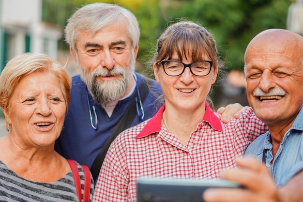 Coppie di anziani che si fanno selfie con lo smartphone Riunione di vecchi amici che si divertono all'aperto insieme