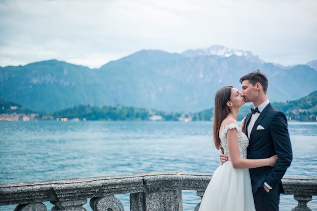 Coppie di cerimonia nuziale che baciano sullo sfondo di un lago e montagne