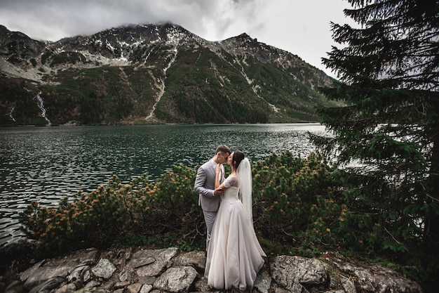 Coppie di cerimonia nuziale che baciano vicino al lago in montagne di Tatra in Polonia, Morskie Oko