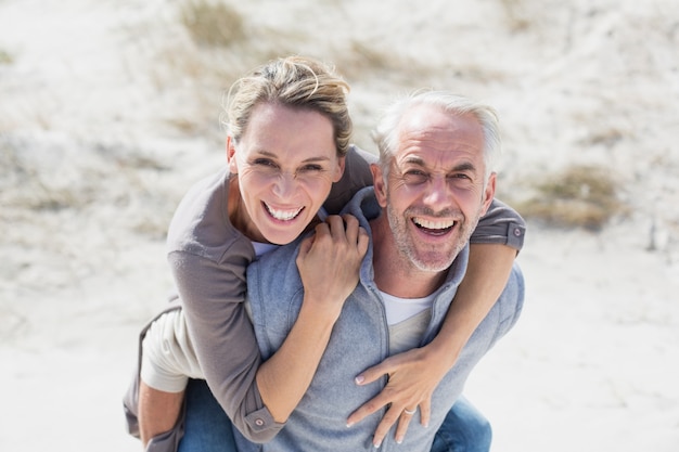 Coppie di risata che sorridono alla macchina fotografica sulla spiaggia