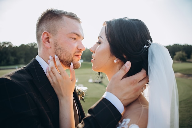 Coppie eleganti che camminano al tramonto, storia d'amore, ritratto della sposa e dello sposo il giorno del matrimonio