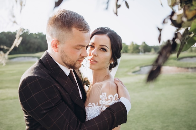 Coppie eleganti che camminano al tramonto, storia d'amore, ritratto della sposa e dello sposo il giorno del matrimonio