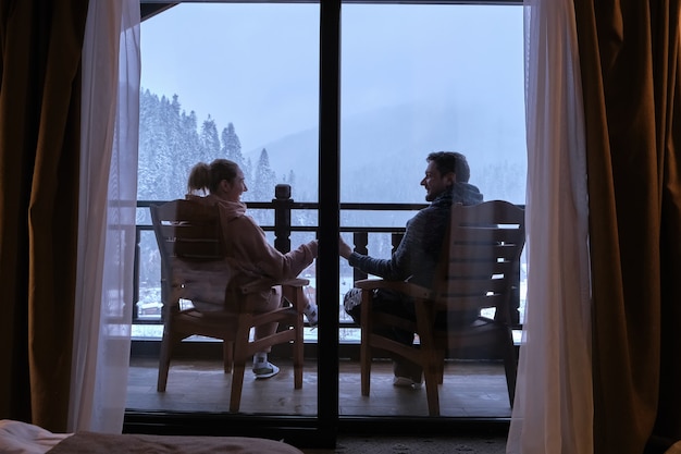 Coppie felici che bevono caffè sul balcone di un hotel di montagna con una bellissima vista sulle montagne