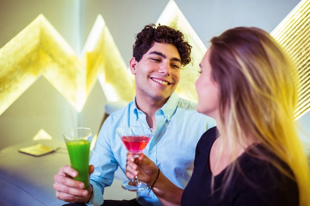 Coppie felici che godono del cocktail in night-club