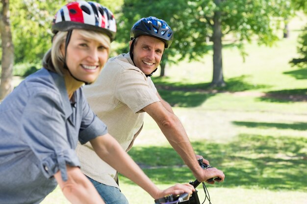 Coppie felici che guidano le biciclette in parco