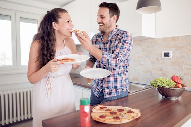 Coppie felici che mangiano pizza nella loro cucina