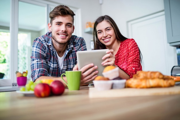 Coppie felici che mangiano prima colazione e che utilizzano compressa a casa