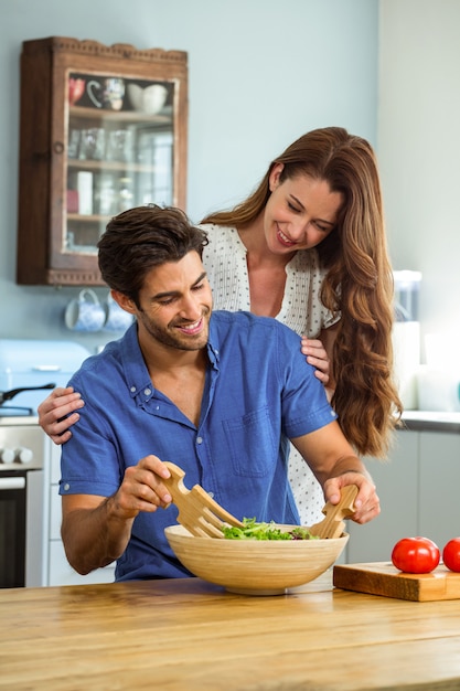 Coppie felici che mescolano un'insalata in cucina