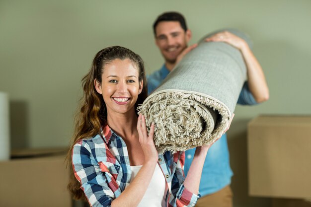 Coppie felici che portano coperta arrotolata nella loro nuova casa