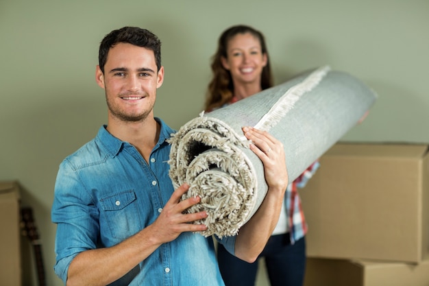 Coppie felici che portano coperta arrotolata nella loro nuova casa