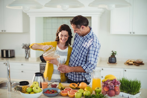 Coppie felici che preparano frullato in cucina