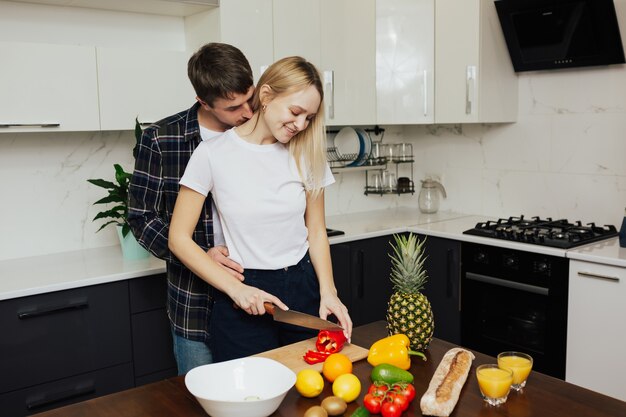 Coppie felici che preparano insalata e succo di frutta fresco.