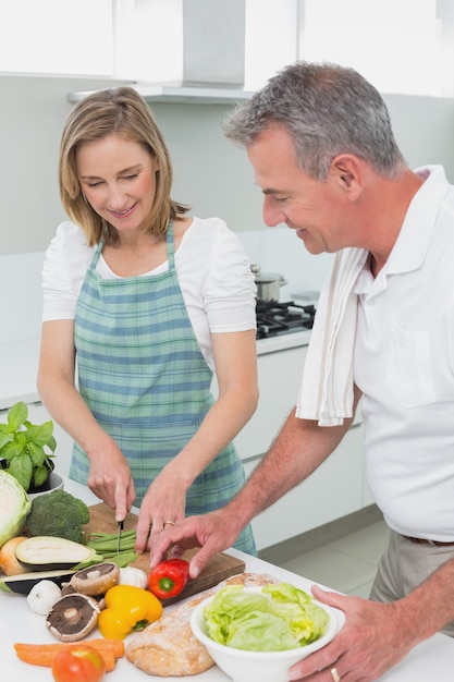 Coppie felici che preparano insieme alimento nella cucina