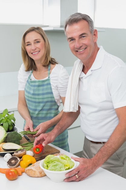 Coppie felici che preparano insieme alimento nella cucina