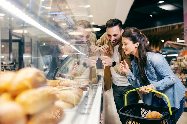 Coppie felici che scelgono pasticceria al reparto panetteria al supermercato