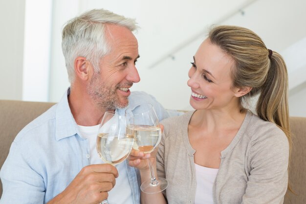 Coppie felici che si siedono sullo strato che tosta con il vino bianco