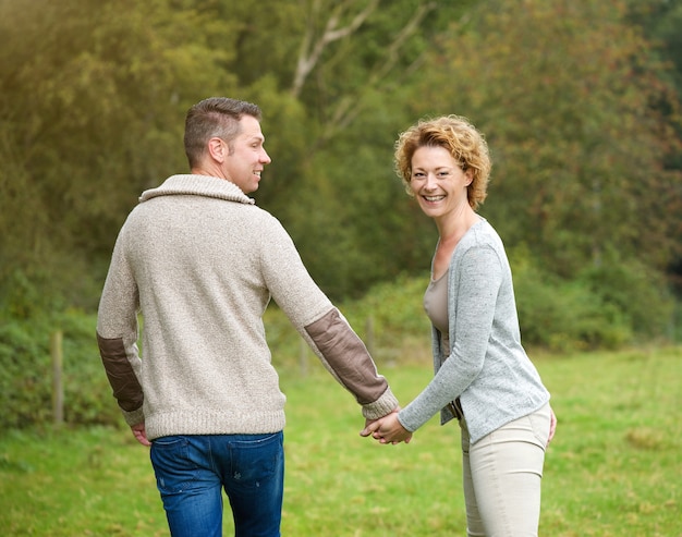 Coppie felici che si tengono per mano e che camminano all&#39;aperto