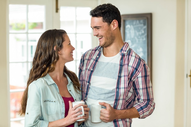 Coppie felici che stanno con la tazza di tè e che si guardano