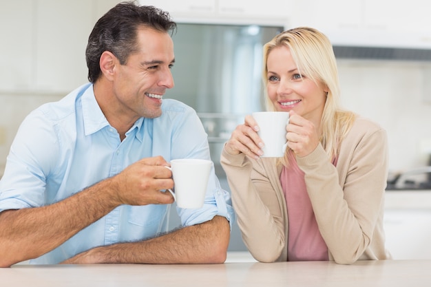 Coppie felici con le tazze di caffè in cucina