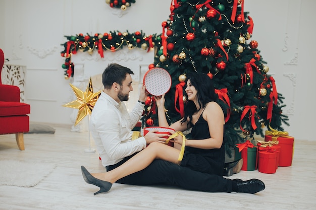 Coppie felici con regalo di Natale isolato sopra il fondo delle luci