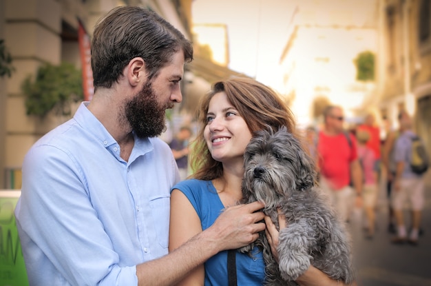 Coppie felici con un cucciolo che cammina nella città