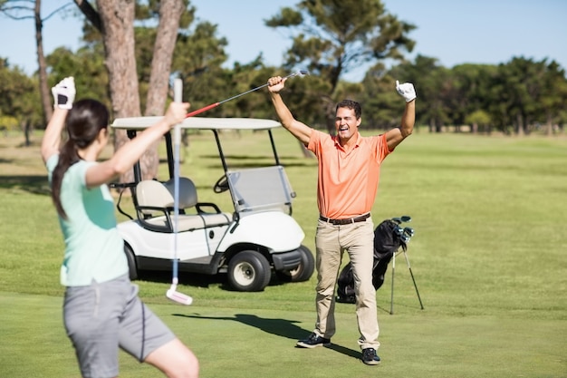 Coppie felici del giocatore di golf con le braccia alzate