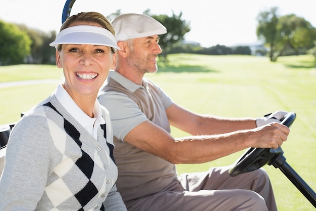 Coppie felici di golf che guidano nel loro carrozzino