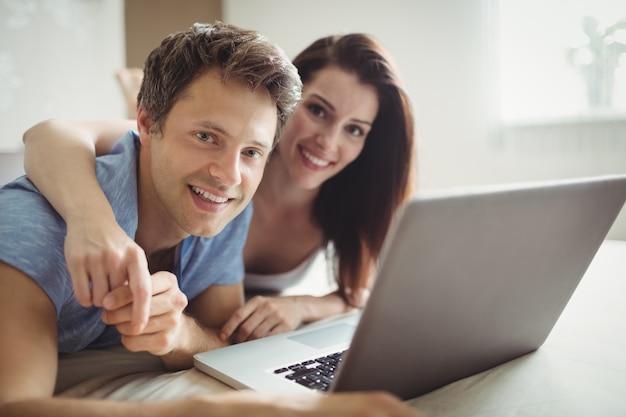 Coppie felici facendo uso del computer portatile sul letto