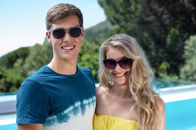 Coppie felici in occhiali da sole che stanno vicino allo stagno