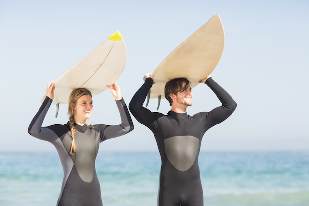 Coppie felici in tavola da surf che trasportano spese generali della tavola