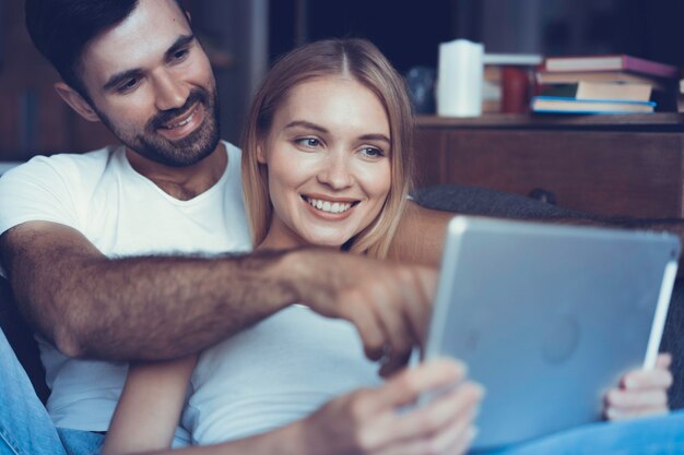 Coppie felici nell'amore che navigano sul tablet a casa.