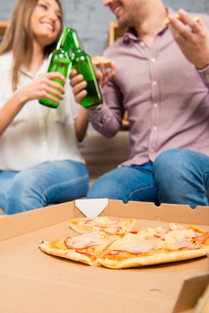 Coppie felici nell'amore che trascorrono le vacanze con pizza e birra