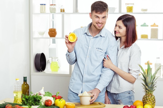 Coppie felici nell'amore in cucina facendo un sano succo di arancia fresca