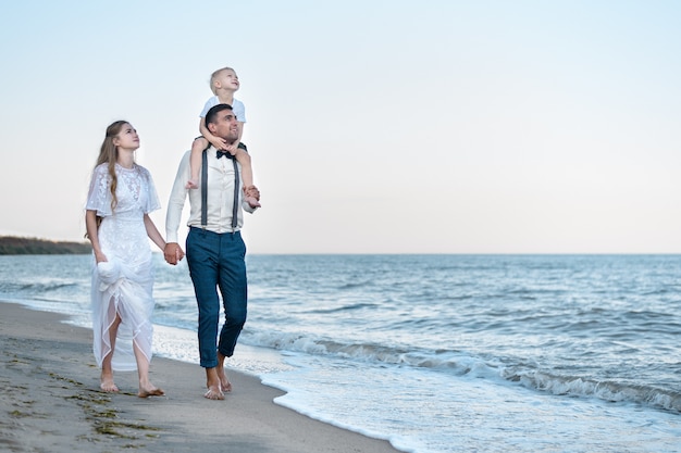 Coppie felici sulla spiaggia del mare al ricorso. Camminando lungo la riva del mare. Concetto di vacanza in famiglia.