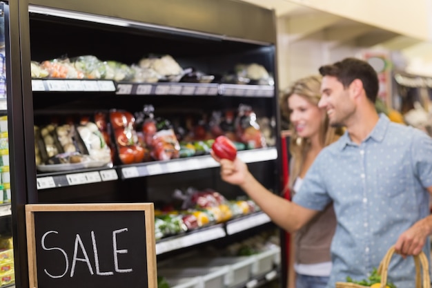 Coppie luminose sorridenti che comprano prodotti alimentari