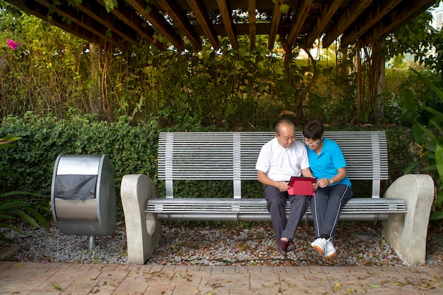 Coppie maggiori che leggono insieme un tablet mobile nel parco