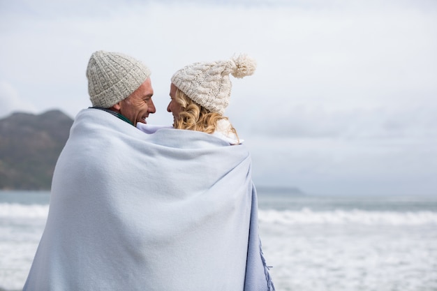 Coppie mature avvolte in coperta sulla spiaggia