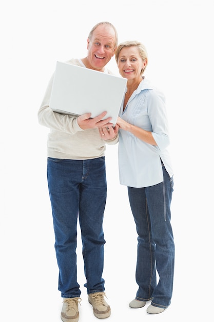 Coppie mature che sorridono alla macchina fotografica con il computer portatile